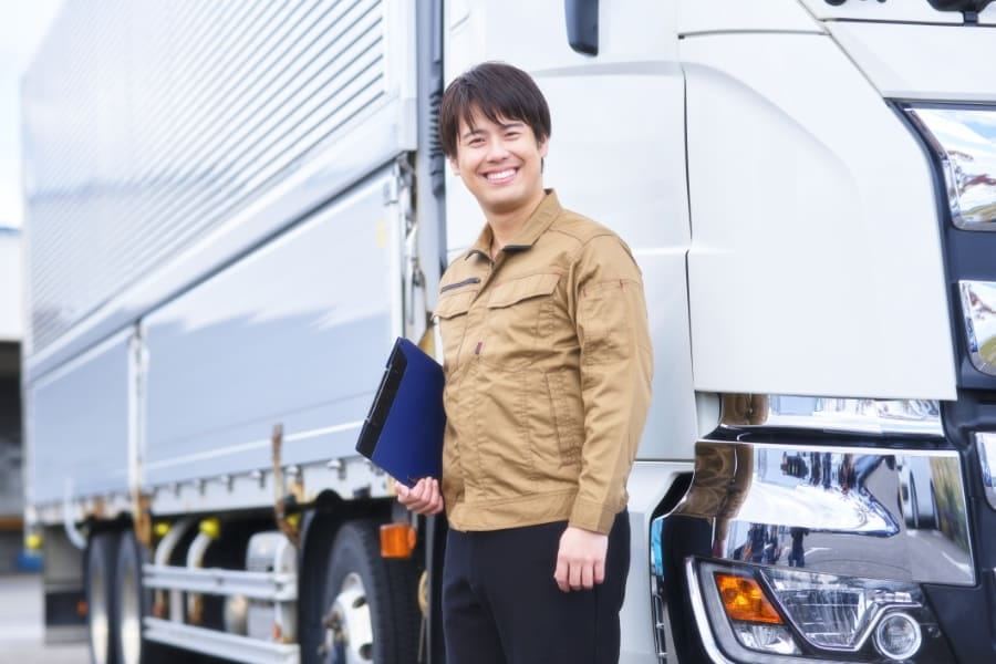トラックの前で笑顔を見せる男性